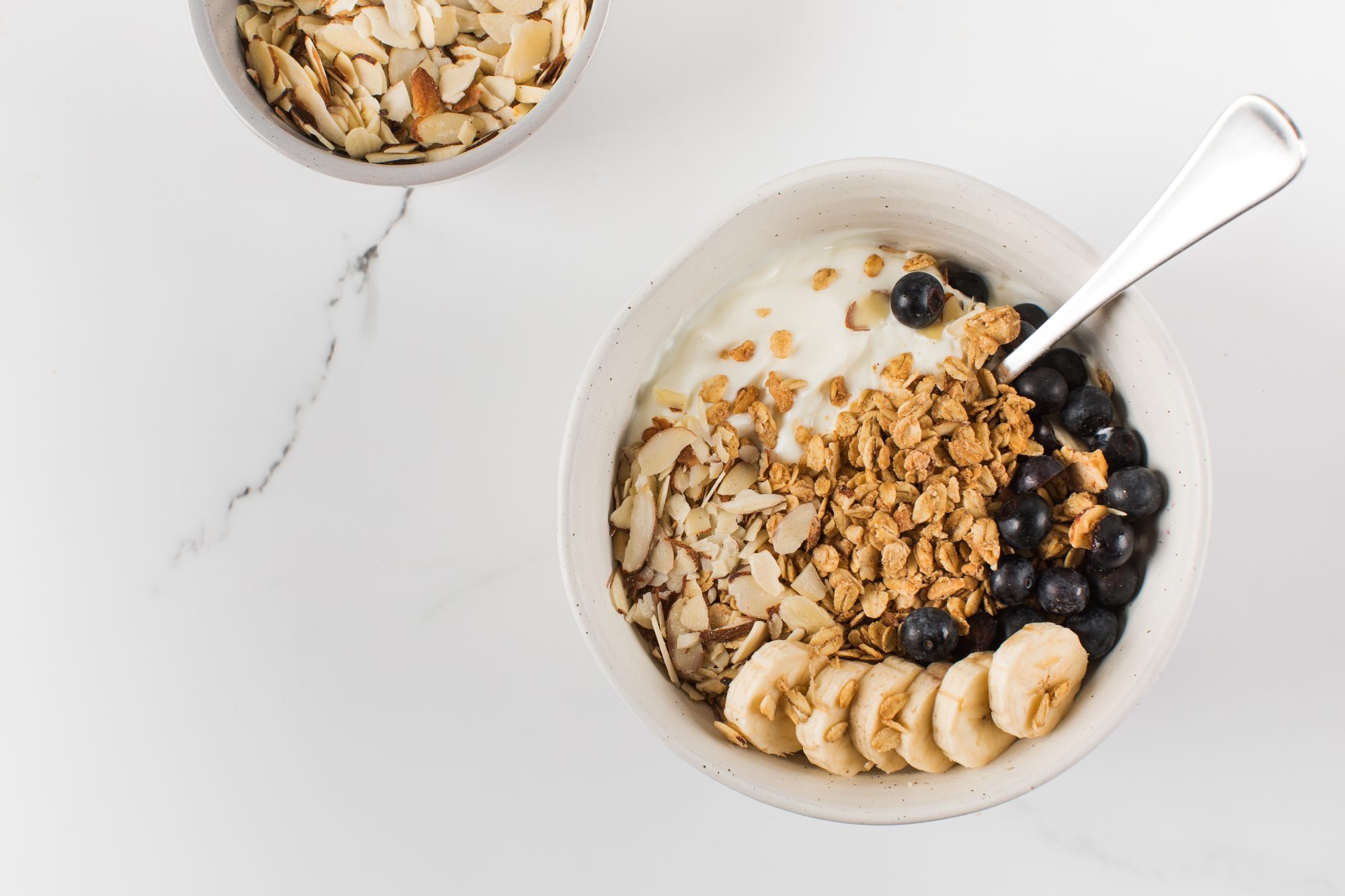 Homemade granola with Greek yogurt, almonds, blueberries and banana in a bowl. Copy space Vancouver office pantry service and healthy vending service