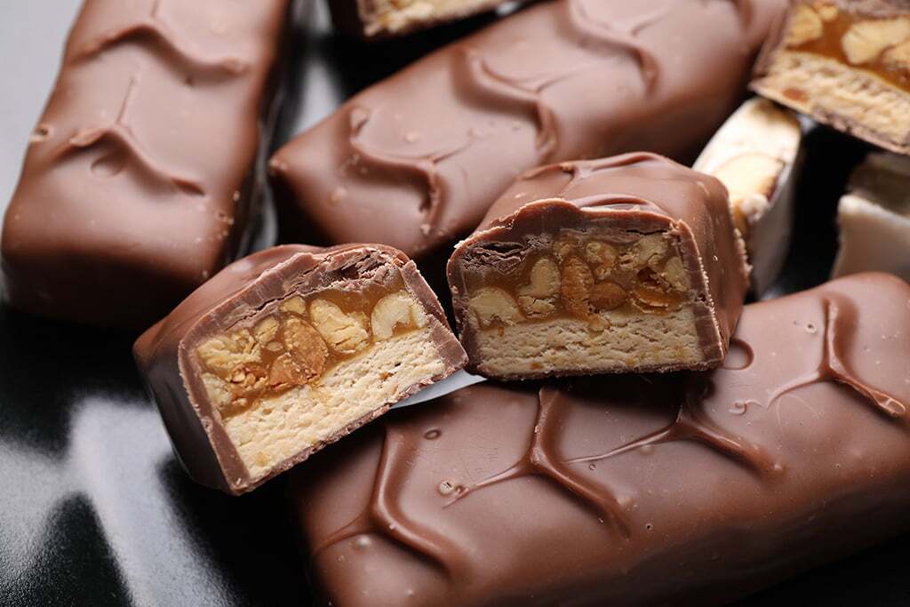 Tasty chocolate bars with nougat and nuts on black plate, closeu Omaha vending service and office coffee