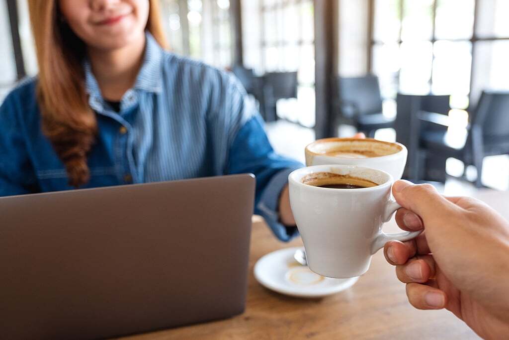 Closeup image of a woman and a man clinking coffee cups together San Diego office coffee solutions and snack vending machines