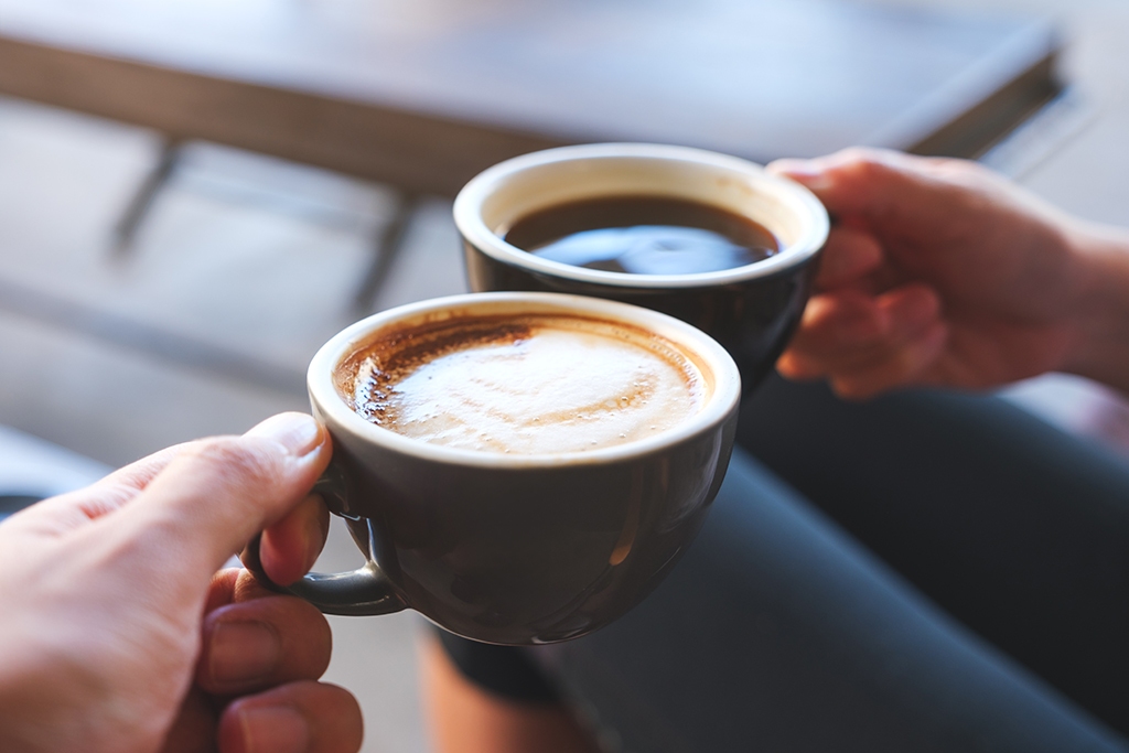 Closeup image of a couple people clinking coffee mugs in cafe office coffee service and snack vending machines in Richmond