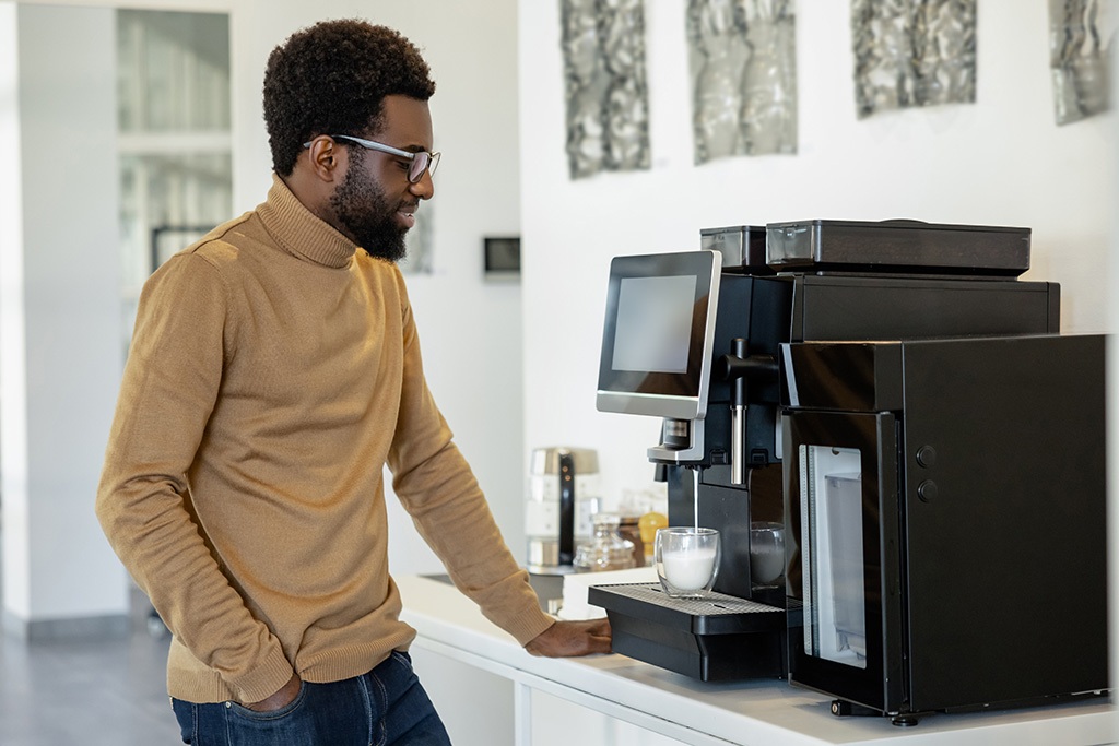 Man office worker using modern coffee machine making coffee in office Irvine office coffee solutions and snack vending machines