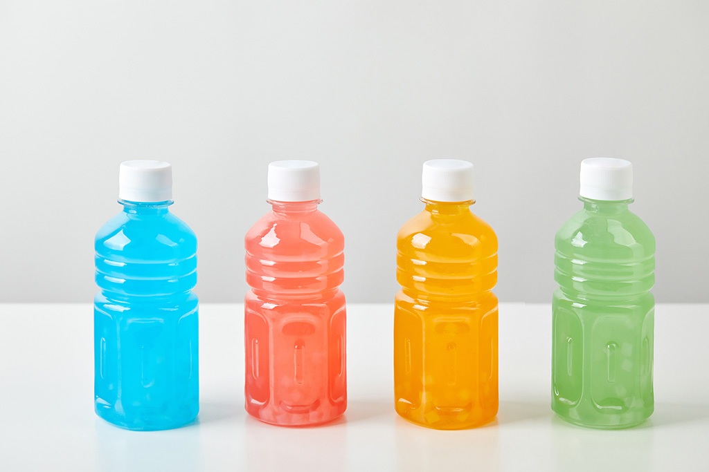 Four small bottles with colorful drinks on white background vending machines and office coffee service in Riverside