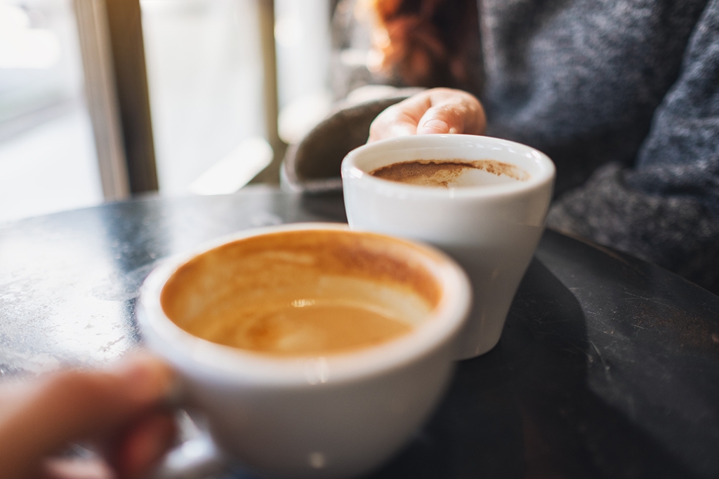 Closeup image of a woman and a man clinking coffee mugs in cafe Wichita office coffee solutions and snack vending machines